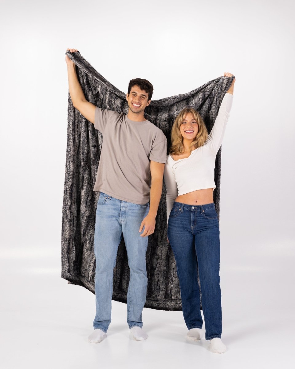 Black Birch Throw luxurious super soft faux fur oversized blanket held by a couple