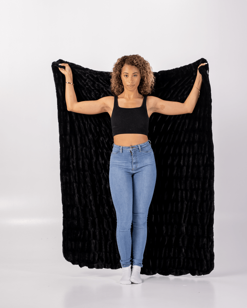 Caviar Black Cloud Throw ultra soft luxury faux fur weighted everyday blanket held by woman.