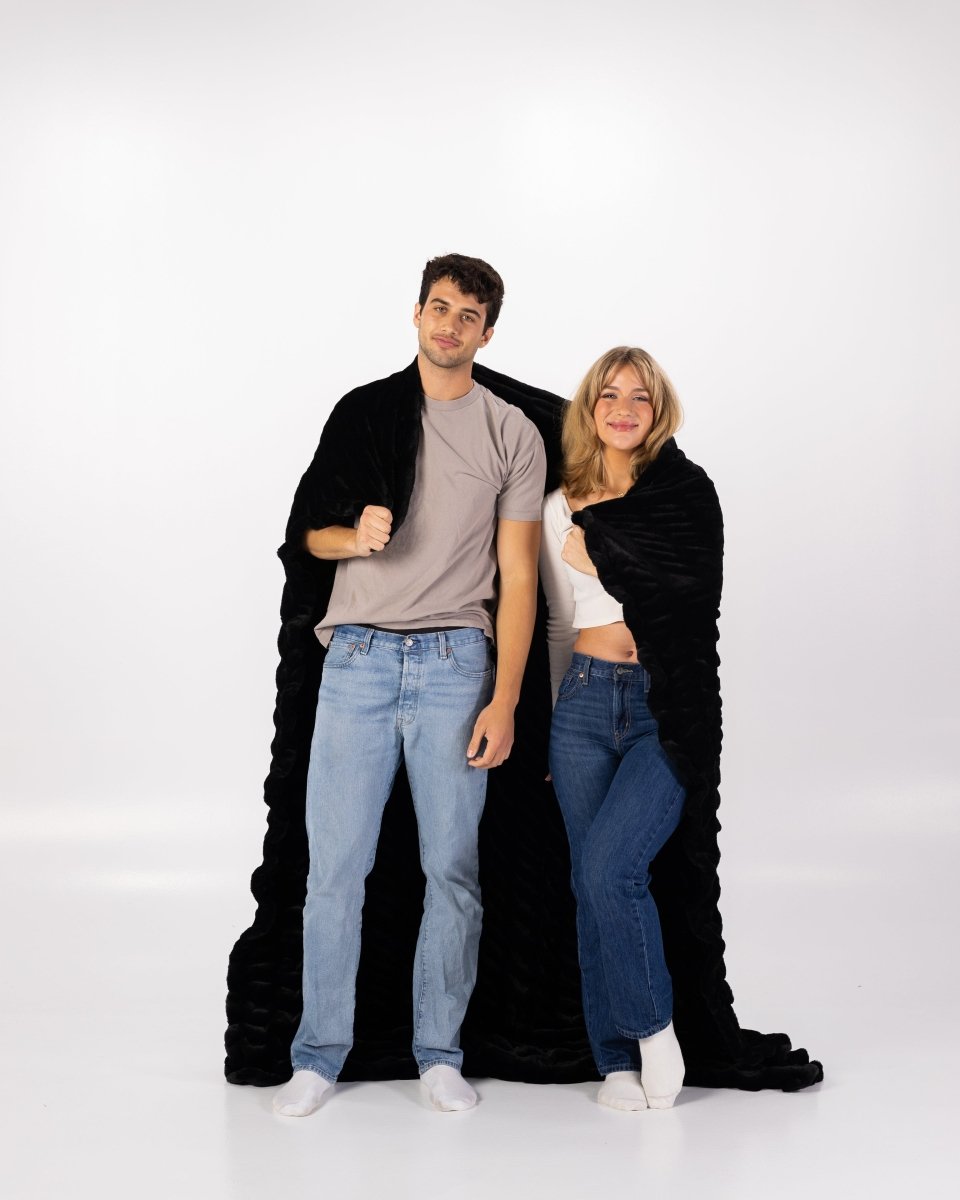Caviar Black Cloud Throw ultra soft luxury faux fur weighted oversized blanket wrapped around couple.