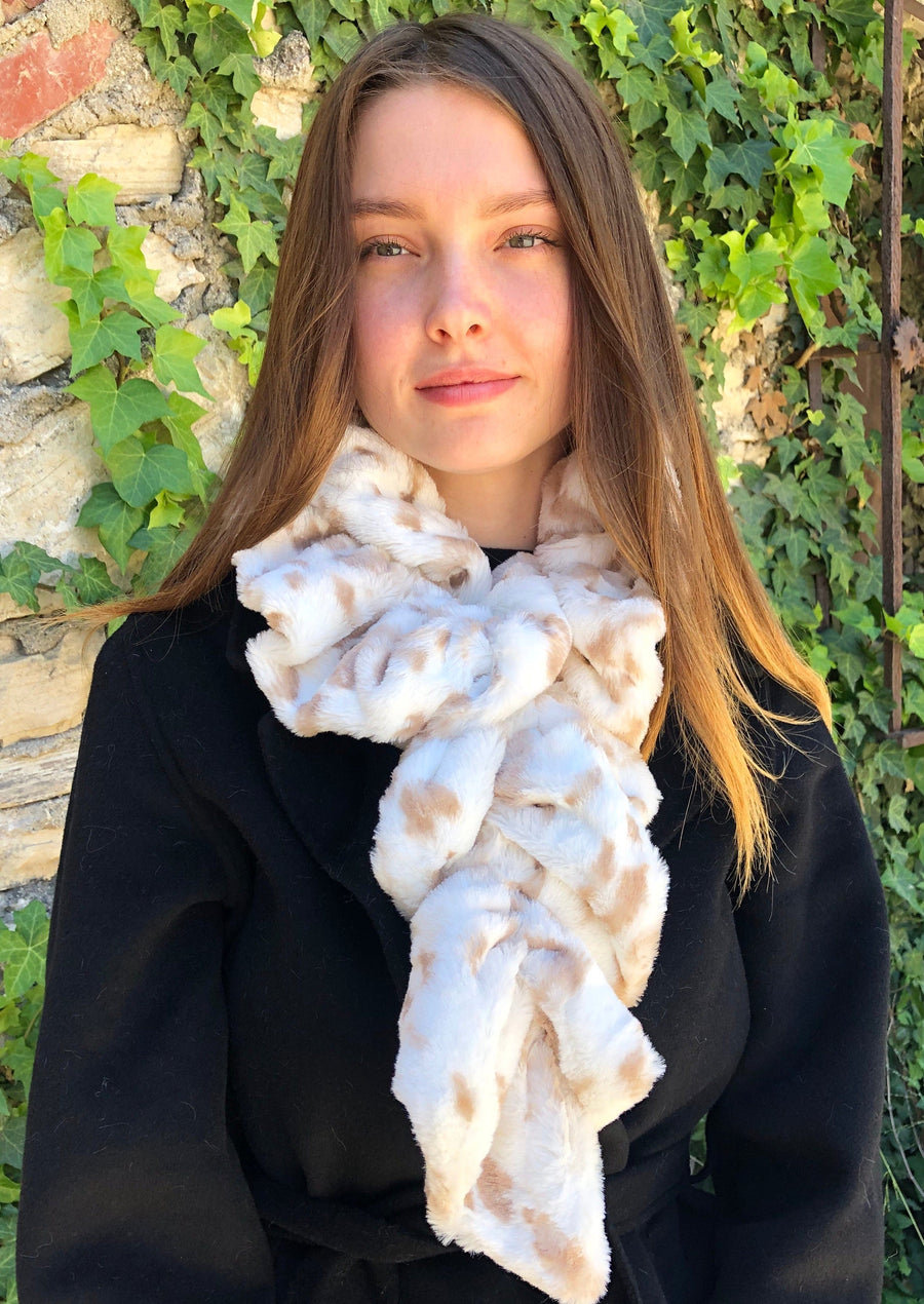 women keeping her Neck Warm with a scarf-like white with warped-dots of light-brown colored Neck Warmer which is the called the Snow Leopard Neck Warmer