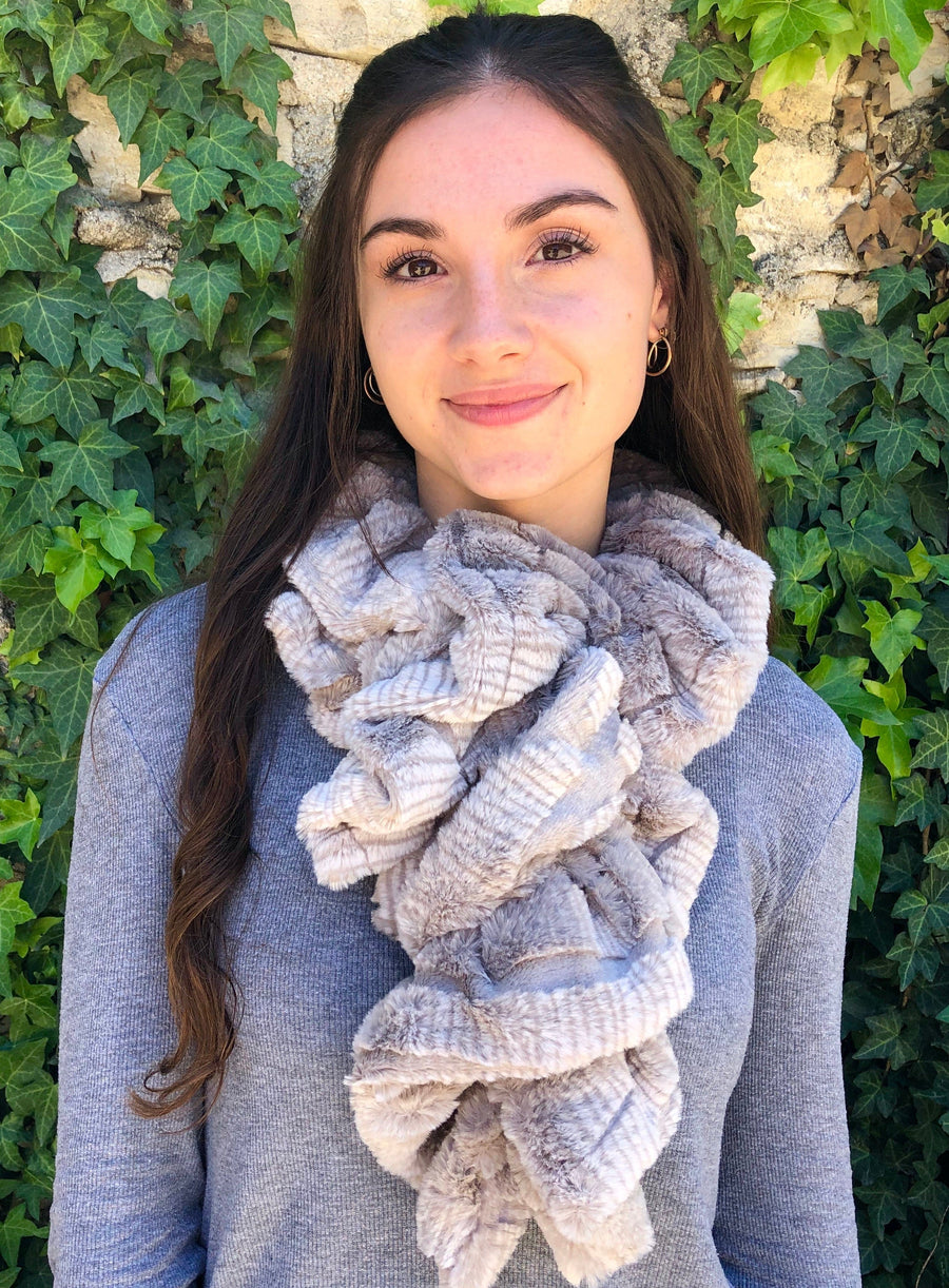 women keeping her Neck Warm with a scarf-like dark brown-purple with soft white stripes on the edge colored Neck Warmer which is the called the Stone Neck Warmer