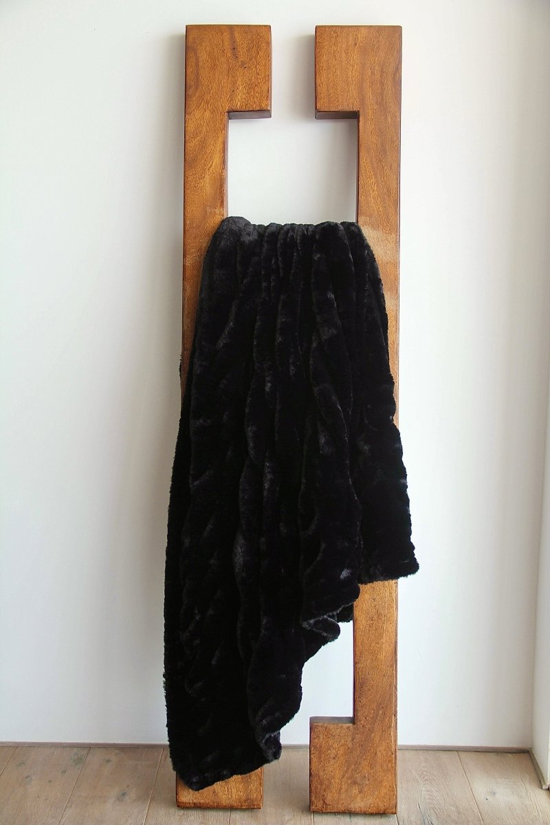 Caviar Black Cloud Throw ultra soft luxury faux fur weighted blanket draped in living room.