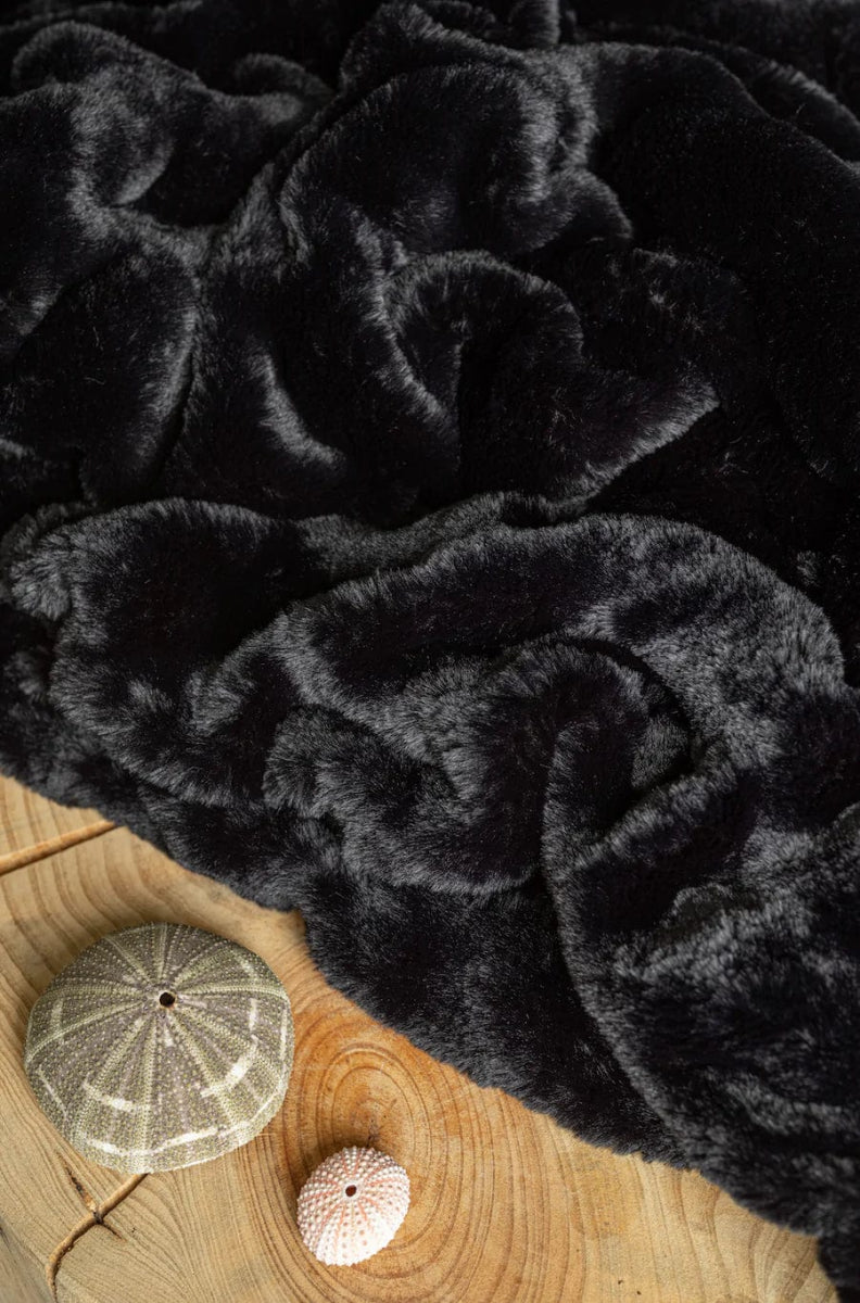 Caviar Black Cloud Throw ultra soft luxury faux fur weighted blanket up close by beach