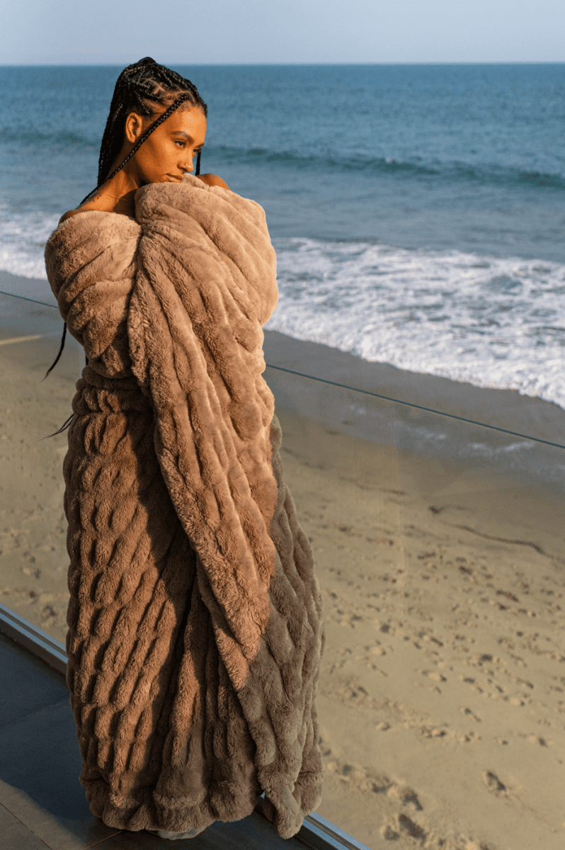Mocha Brown Cloud Throw ultra soft luxury faux fur weighted blanket wrapped around woman in luxury home by beach