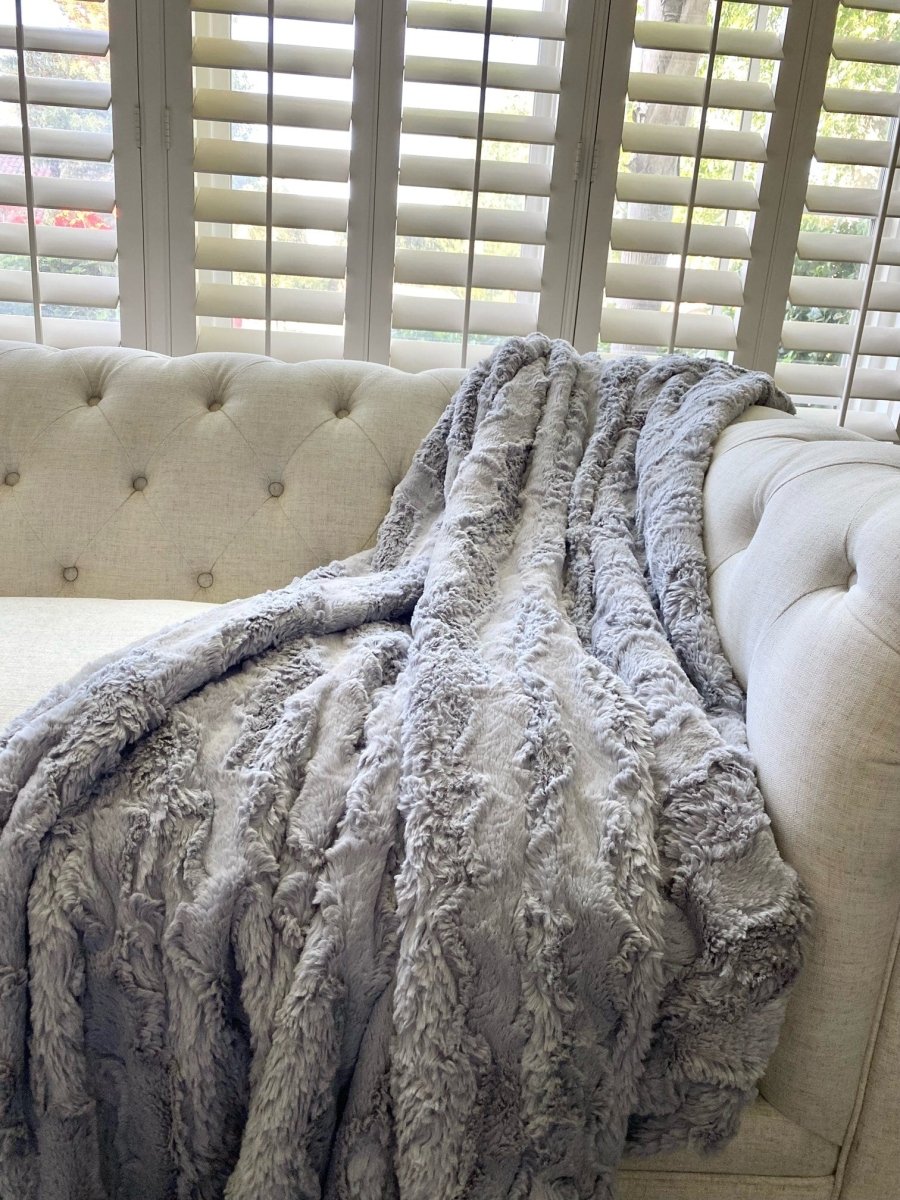 Silver gray throw  in ultra soft high quality faux fur draped over couch.